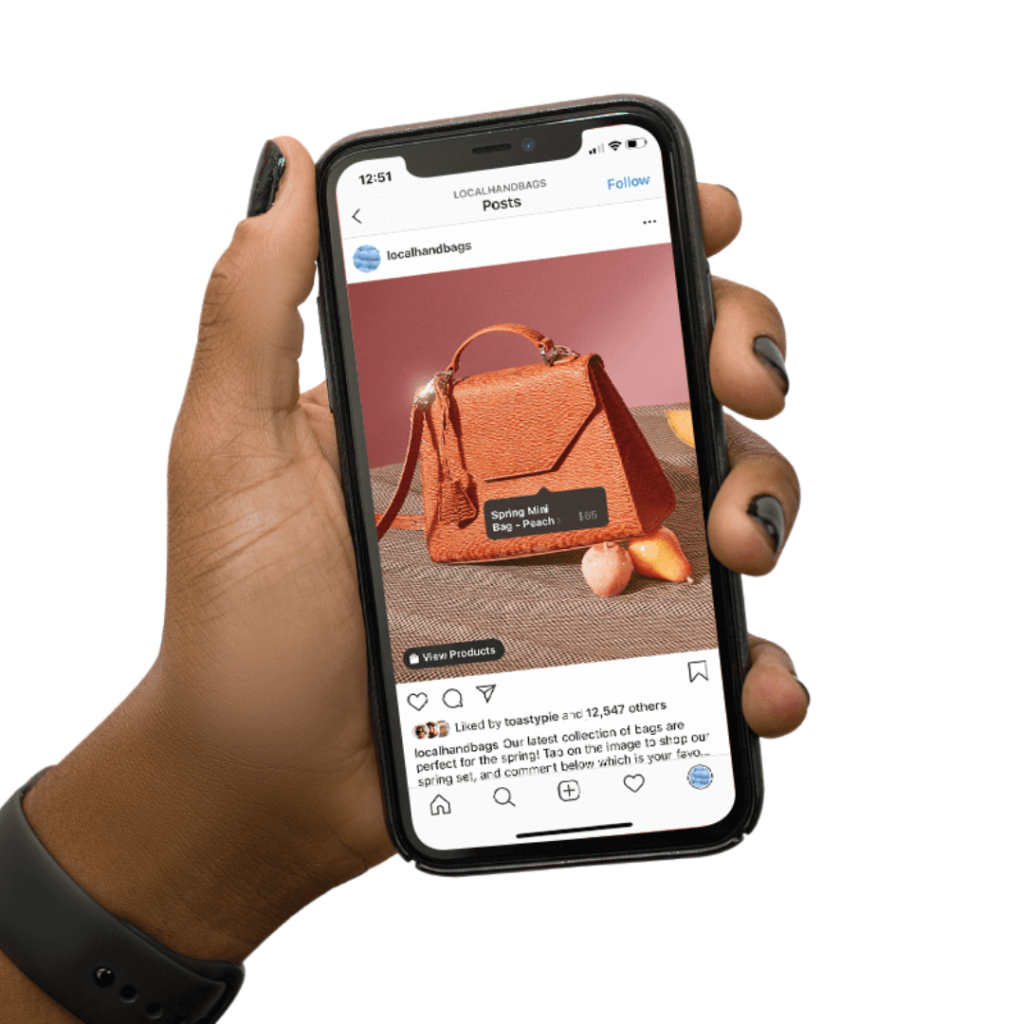 A hand holding a phone. On the screen is an Instagram post of brown handbag